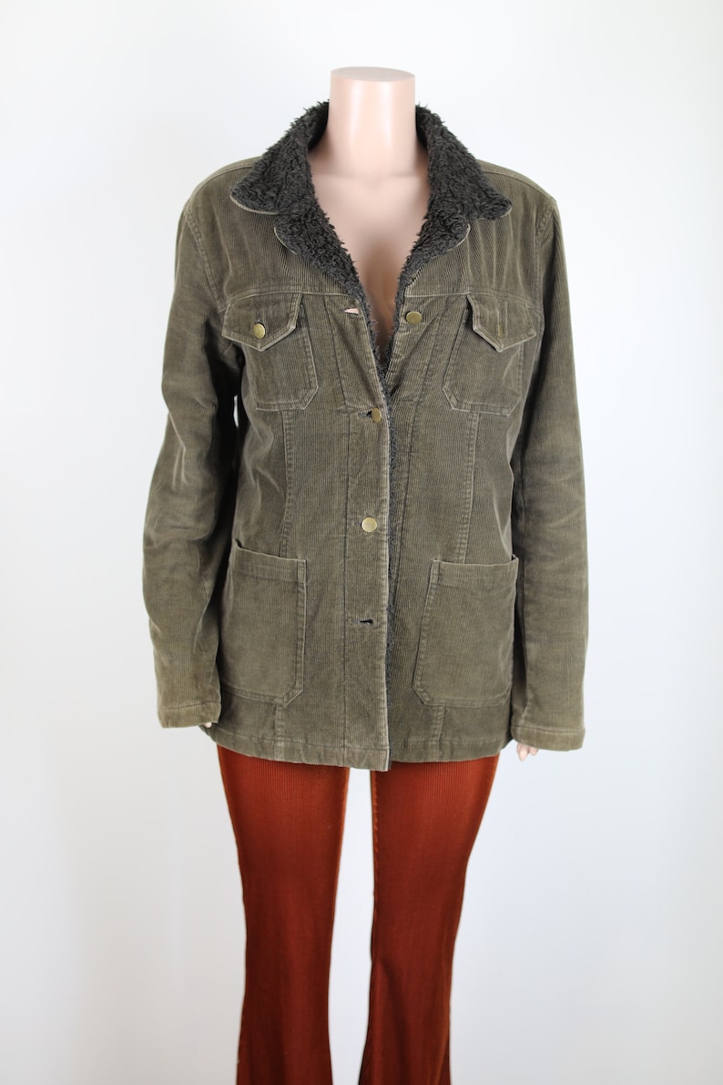 May include: A green corduroy jacket with a brown faux fur collar. The jacket has a button closure and two large pockets on the front.