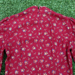 May include: A red dress with a small floral print. The dress has a high neck and long sleeves.
