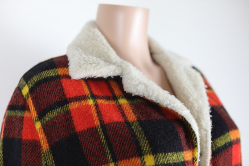 May include: A red, black, yellow and green plaid jacket with a white faux fur collar.