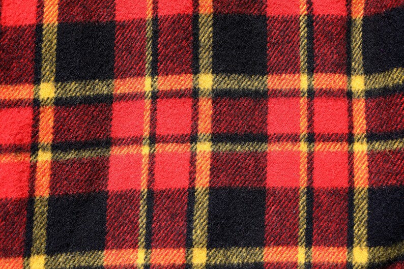 May include: Red, black and yellow plaid fabric with a woven texture.