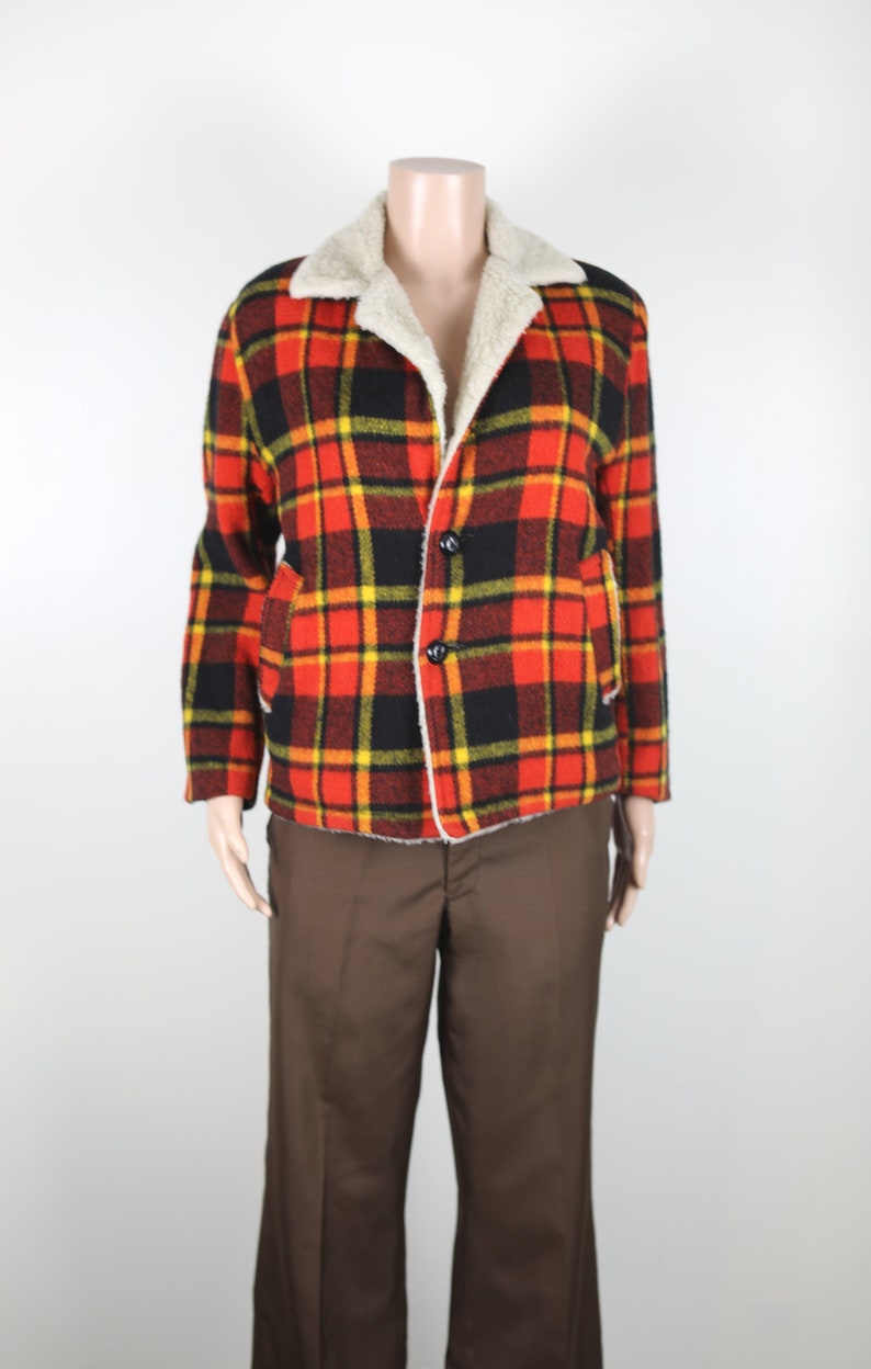 May include: A red, black and yellow plaid jacket with a white faux fur collar. The jacket has a button fastening and two pockets.
