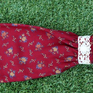 May include: A red fabric sleeve with a white lace trim and a floral pattern.