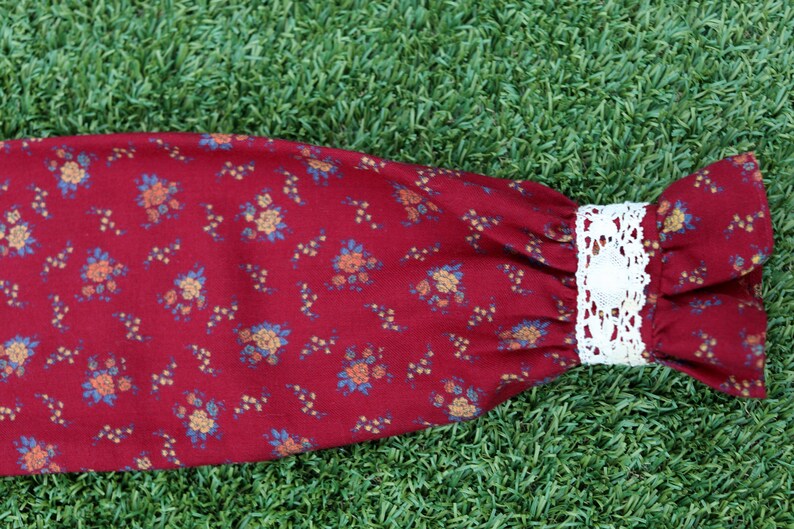 May include: A red fabric sleeve with a white lace trim and a floral pattern.