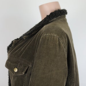 May include: A brown corduroy jacket with a black faux fur collar. The jacket has a button closure and a pocket on the left side.