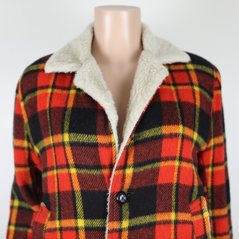 May include: A red, black and yellow plaid jacket with a white sherpa lining. The jacket has a button closure and two pockets.