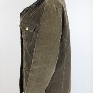 May include: A brown corduroy jacket with a black faux fur collar. The jacket has a button closure and two pockets.