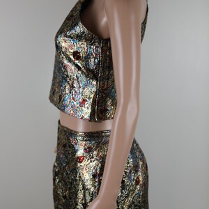 May include: A two-piece outfit with a gold, blue, and red patterned design. The top is a cropped, one-shoulder style. The skirt is a midi length.