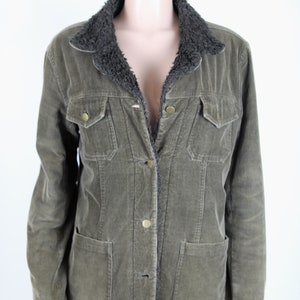 May include: A green corduroy jacket with a brown faux fur collar. The jacket has a button closure and two flap pockets.