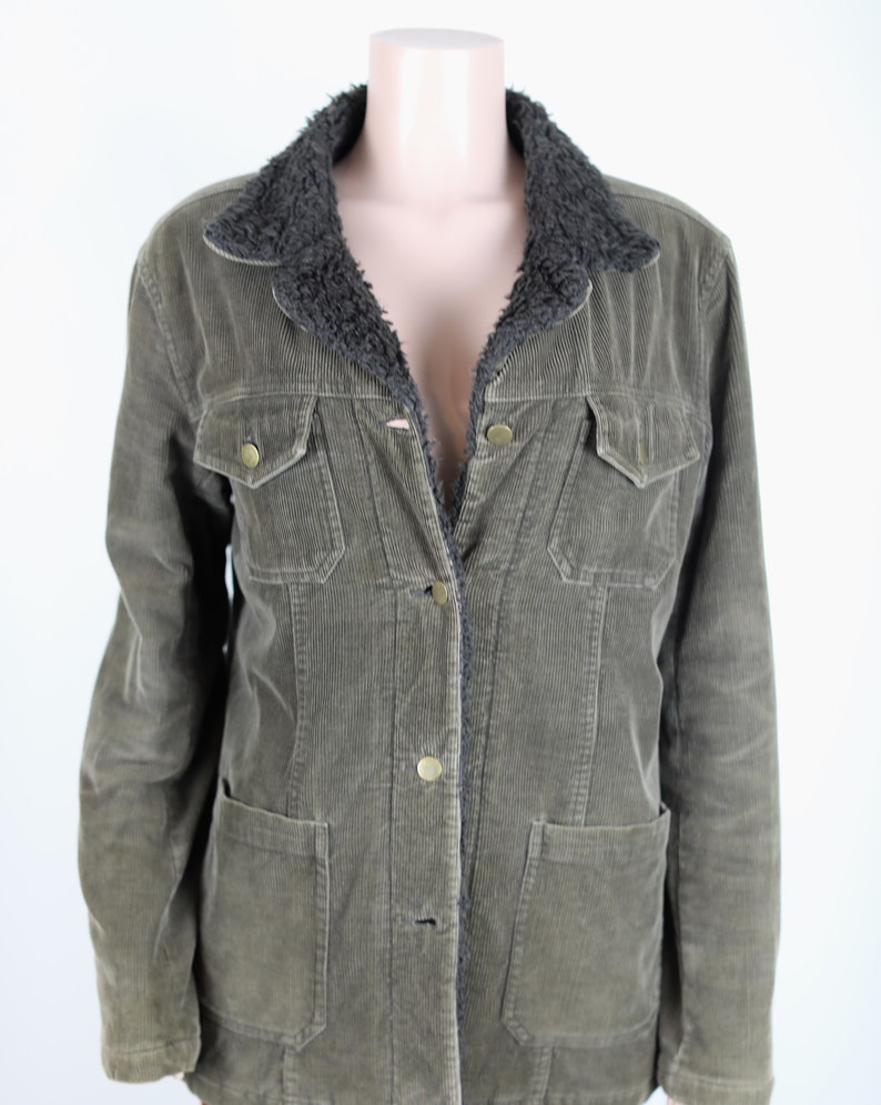 May include: A green corduroy jacket with a brown faux fur collar. The jacket has a button closure and two flap pockets.