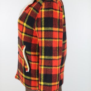 May include: A red, black and yellow plaid jacket with a faux fur collar. The jacket is made of a thick, warm fabric and has a classic, vintage style.