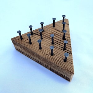 May include: A wooden triangle game board with 18 metal nails hammered into the surface. The board is made of a light brown wood with a natural grain pattern.