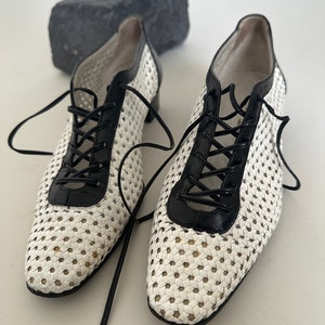 Puede incluir: Zapatos de cuero tejido blanco y negro con cordones y punta puntiaguda.