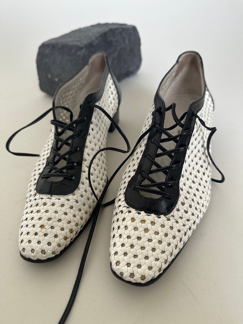 May include: White and black woven leather lace-up shoes with a pointed toe.