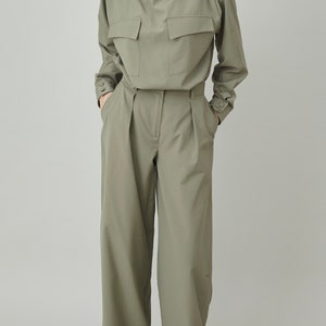 May include: A green, long-sleeved collared shirt with two large pockets on the front, paired with matching green wide-leg pants.