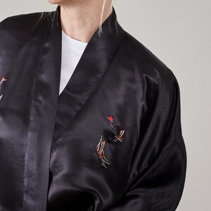 May include: A black satin robe with embroidered sailboats and a red sun. The robe has a shawl collar and long sleeves.