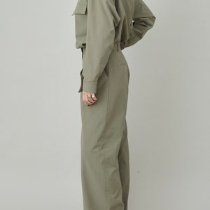 May include: A green collared shirt with long sleeves and a matching pair of wide-leg pants.