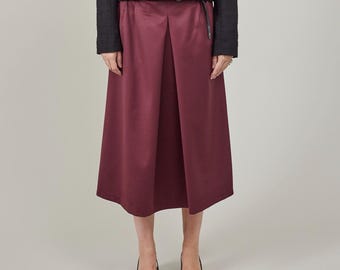 May include: A burgundy midi skirt with a pleated front and a black belt.