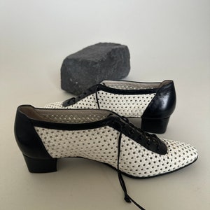 May include: White and black woven leather shoes with a lace-up closure and a low block heel.