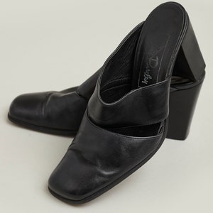 Puede incluir: Mulas de tac&oacute;n de cuero negro con puntera cuadrada y dise&ntilde;o de corte. Los zapatos tienen un tac&oacute;n grueso y est&aacute;n etiquetados como "Dorothy Perkins".