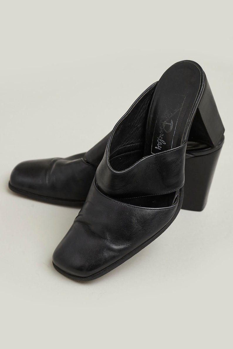 Puede incluir: Mulas de tac&oacute;n de cuero negro con puntera cuadrada y dise&ntilde;o de corte. Los zapatos tienen un tac&oacute;n grueso y est&aacute;n etiquetados como "Dorothy Perkins".