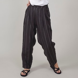 May include: Black and white striped linen pants with a high waist and a button closure. The pants have a wide leg and a relaxed fit.