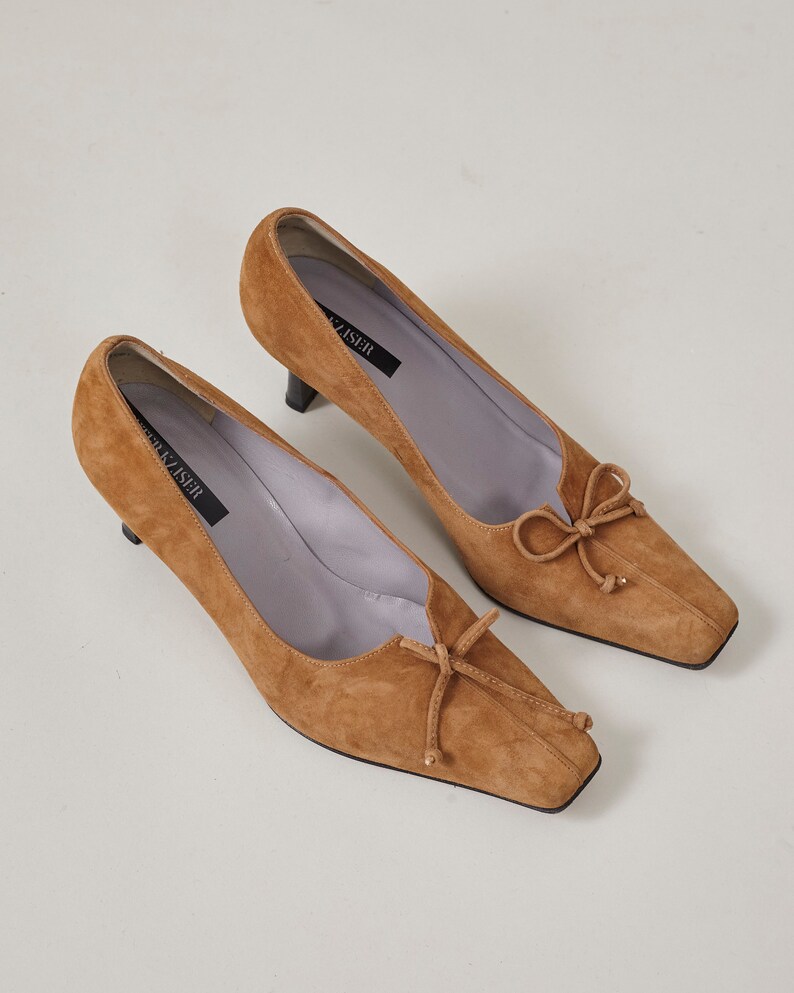 K&ouml;nnte beinhalten: Ein Paar braune Wildlederschuhe mit Absatz, quadratischer Spitze und Schleife auf dem Spann. Die Schuhe sind mit "Frank Ziser" gekennzeichnet.
