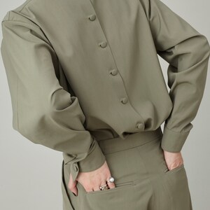 May include: A sage green long-sleeved shirt with a button-up back and a matching pair of pants.