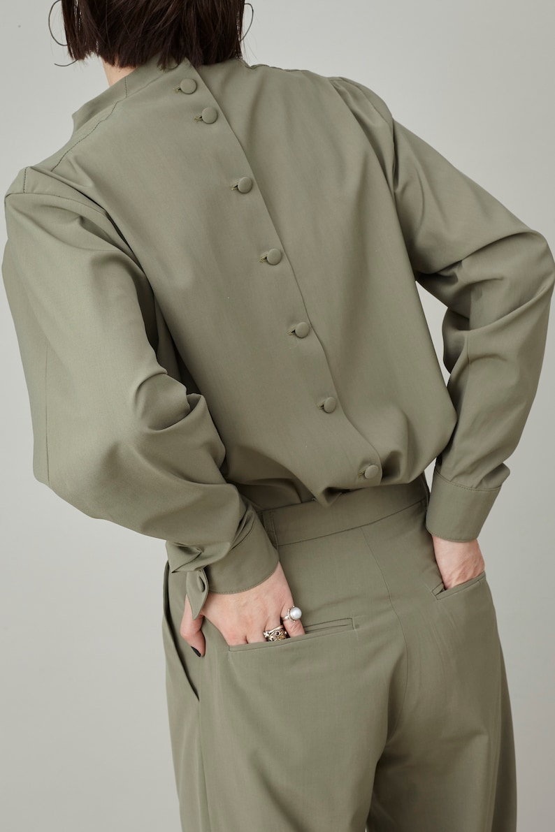 May include: A sage green long-sleeved shirt with a button-up back and a matching pair of pants.