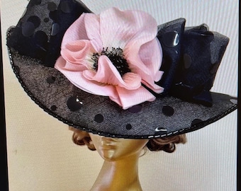 Sombrero Ascot de ala ancha con una gran amapola rosa sobre una red negra con lunares.