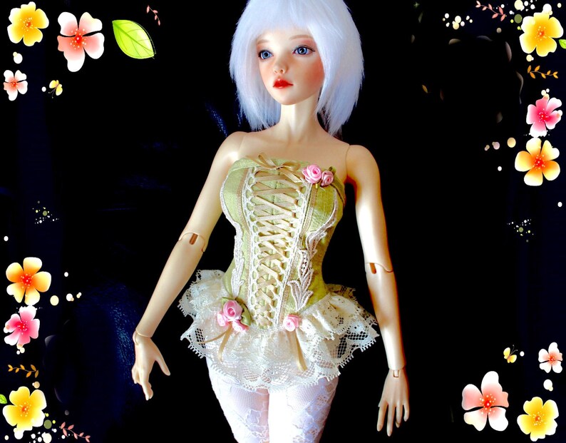 May include: A doll with white hair and blue eyes, wearing a green corset with lace detailing and pink rose accents. The doll's outfit includes a white lace skirt and white patterned leggings. The background is black with floral decorations.