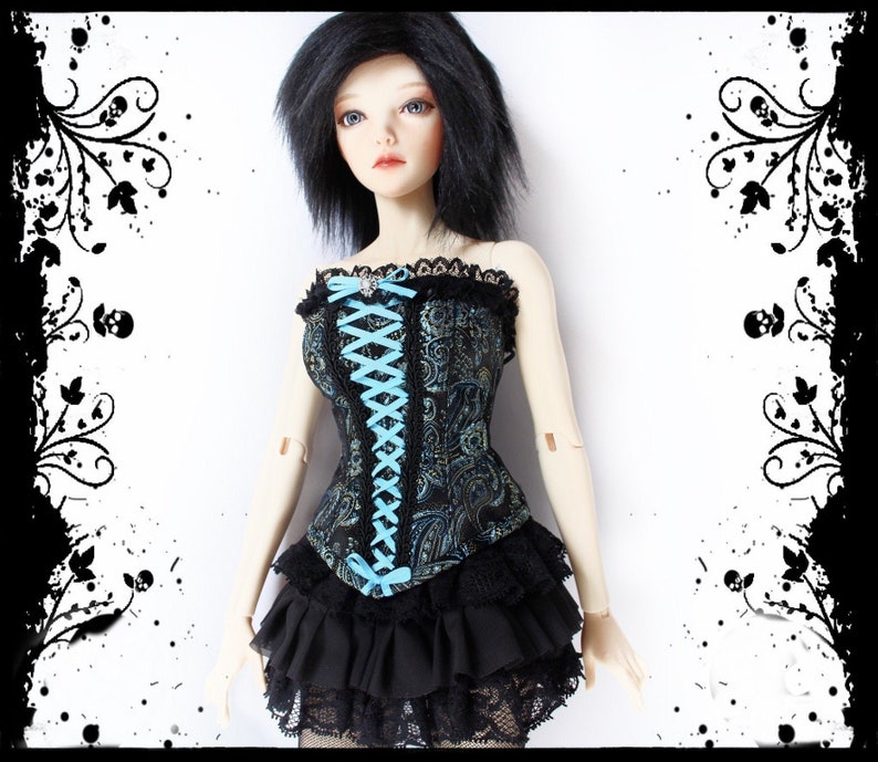 May include: A doll wearing a black and teal corset with a floral pattern, laced with light blue ribbon. The corset is paired with a black ruffled skirt and lace trim. The doll has black hair and is set against a white background.