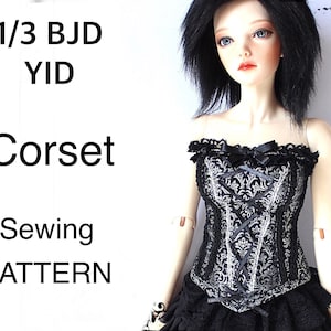 May include: A black and silver corset with a floral pattern, lace trim, and ribbon detailing. The corset is part of a sewing pattern for a 1/3 BJD YID doll. The text "Corset Sewing Pattern" is visible.