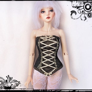 May include: A doll wearing a black corset with gold trim and a crisscross lace design. The corset has gold bows and is paired with white lace pants. The doll has white hair and is set against a white background.