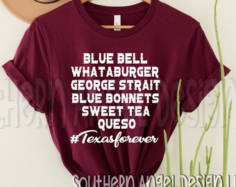 May include: Burgundy t-shirt with white text that reads "Blue Bell, Whataburger, George Strait, Blue Bonnets, Sweet Tea, Queso #Texasforever". The shirt is hanging on a wooden hanger against a white wall.