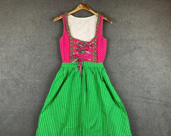 Peut inclure: Une robe de dirndl verte et rose à pois blancs et un corsage rose avec une bordure en dentelle blanche. Le corsage a un laçage sur le devant avec un ruban rose.
