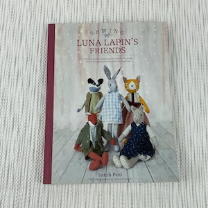 May include: A book titled "Sewing Luna Lapin's Friends" with a white background and a photo of five handmade plush toys. The book cover features the text "Over 20 sewing patterns for heirloom dolls and their exquisite handmade clothing".