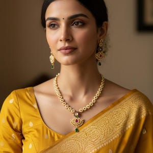 Puede incluir: Un collar de tono dorado con una hilera de pequeñas perlas blancas, un colgante floral central con una piedra rosa y una gema verde colgante en forma de lágrima. Los pendientes a juego presentan un diseño similar con perlas y piedras.