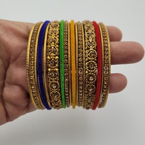 Puede incluir: Un conjunto de brazaletes dorados con intrincados dise&ntilde;os florales y pedrer&iacute;a incrustada. El conjunto incluye brazaletes en varios colores, como azul, verde, amarillo y rojo, creando un accesorio vibrante y llamativo.