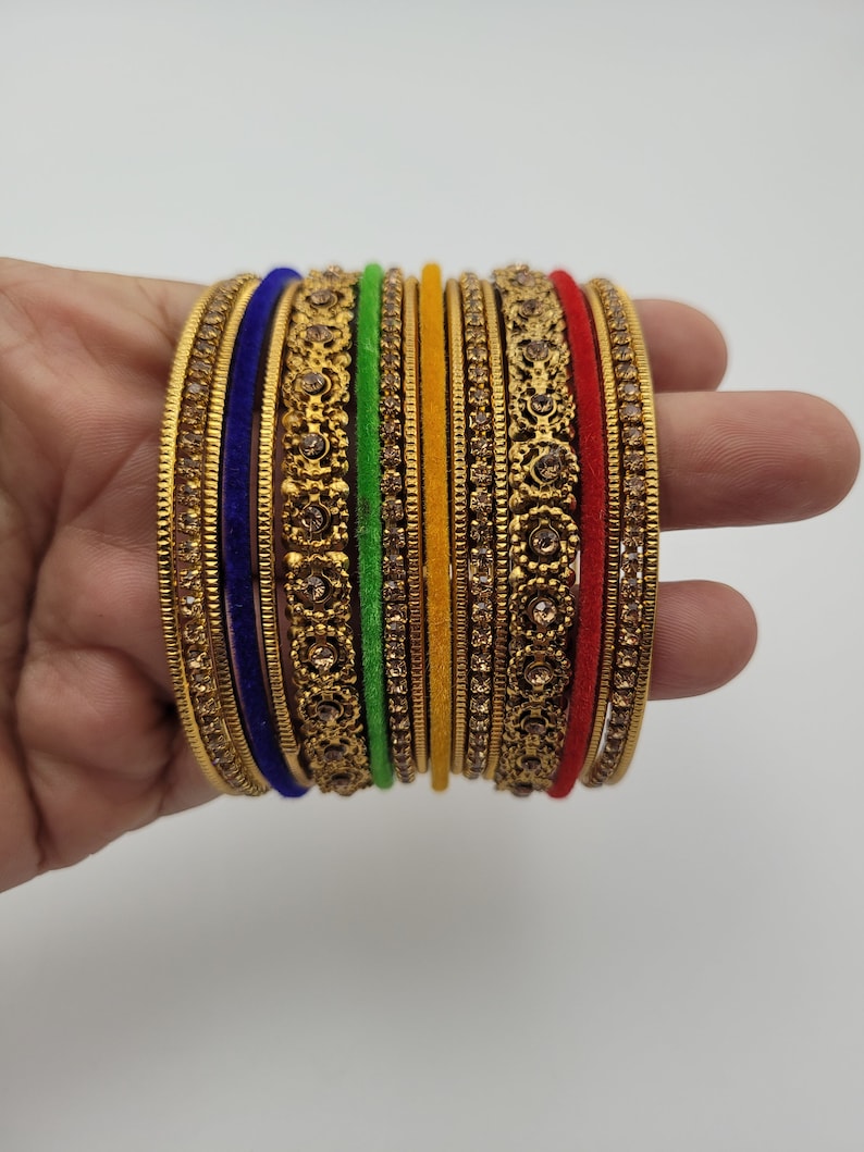 Puede incluir: Un conjunto de brazaletes dorados con intrincados dise&ntilde;os florales y pedrer&iacute;a incrustada. El conjunto incluye brazaletes en varios colores, como azul, verde, amarillo y rojo, creando un accesorio vibrante y llamativo.