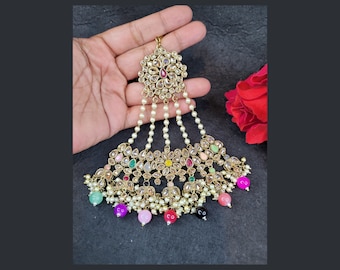 May include: A gold-coloured headpiece with a floral design, featuring clear and colourful gemstones, and dangling pearl strands. The headpiece has a central floral cluster and a fan-shaped lower section with colourful bead accents.