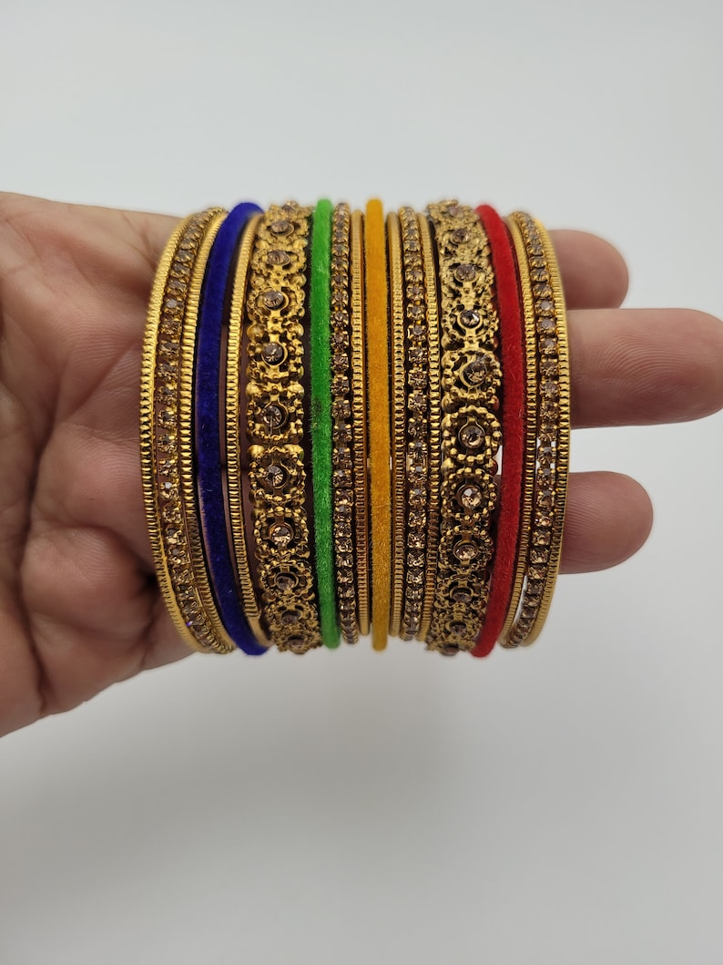 Puede incluir: Un conjunto de pulseras doradas con intrincados dise&ntilde;os florales y gemas incrustadas. El conjunto incluye pulseras en varios colores, como azul, verde, amarillo y rojo, creando un accesorio vibrante y llamativo.