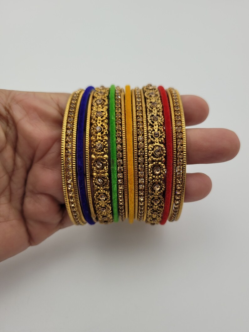 Puede incluir: Un conjunto de pulseras doradas con intrincados dise&ntilde;os florales y pedrer&iacute;a incrustada. El conjunto incluye pulseras en varios colores, como azul, verde, amarillo y rojo, creando un accesorio vibrante y llamativo.