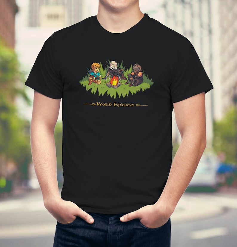 May include: Black t-shirt with a graphic of three video game characters around a campfire. The text "World Explorers" is printed below the graphic.