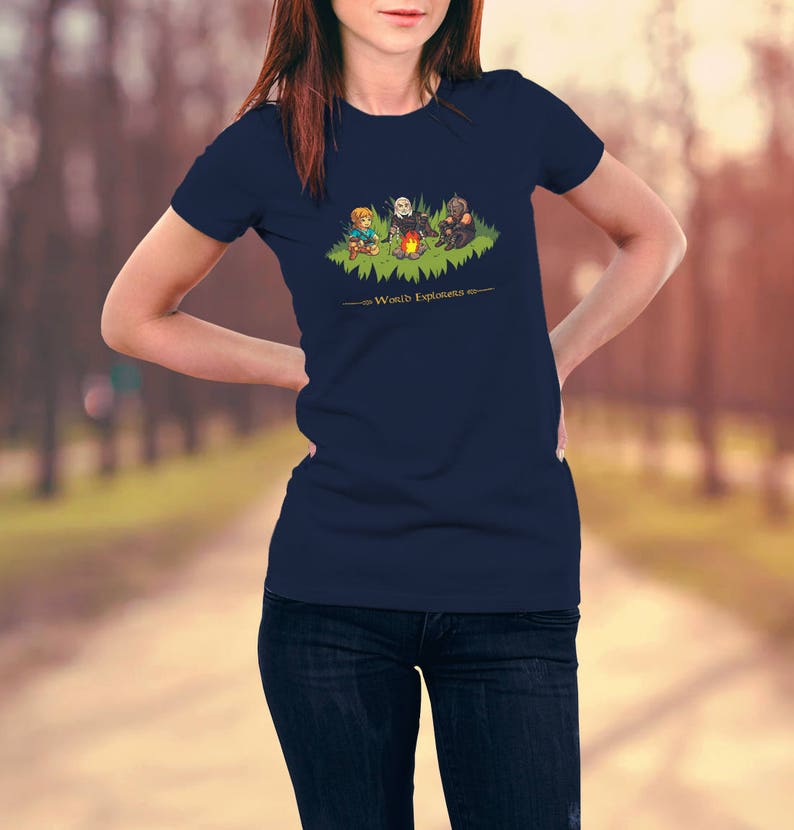 May include: A navy blue t-shirt with a graphic of three cartoon characters sitting around a campfire. The text "World Explorers" is printed below the graphic.