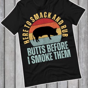 Könnte beinhalten: Schwarzes T-Shirt mit einem Schweinesilhouette-Motiv in einem Retro-Sonnenuntergangsdesign. Der Text lautet: "HERE TO SMACK AND RUB BUTTS BEFORE I SMOKE THEM". Ein humorvolles Design für Grillfans.