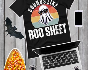 以下が含まれることがあります： 「SOUNDS LIKE BOO SHEET」の文字とサングラスをかけたお化けのグラフィックがプリントされた黒いTシャツ。画像には、ラップトップ、スマートフォン、キャンディーコーン、クモ、コウモリ、メガネも含まれています。