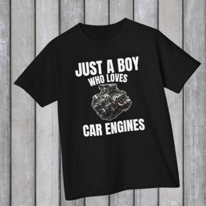 May include: Black t-shirt with the text "JUST A BOY WHO LOVES CAR ENGINES" in white. The shirt features a graphic of a car engine. The t-shirt is made of a soft material and is suitable for casual wear.