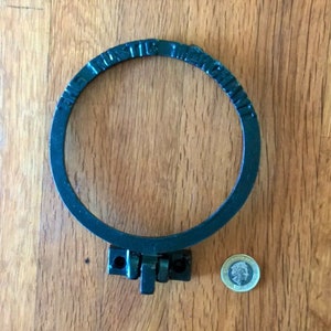 May include: Black metal ring with the words "The Rustic Metal Chain" engraved around the outside. The ring has a hinged clasp.