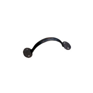 May include: A dark, curved metal door pull with two round mounting plates. The handle has a rustic, aged appearance, suggesting it is made of wrought iron or a similar material. The hardware is designed for a door or cabinet.