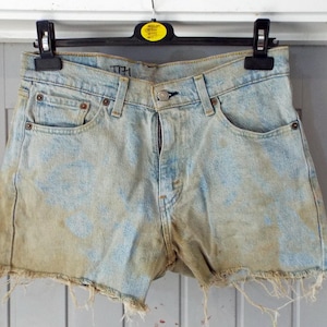 May include: Light blue denim shorts with a faded, distressed look. The shorts have a frayed hem and are slightly bleached.
